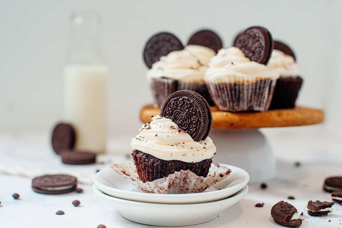 Oreo Cupcake on a plate with a platter of cupcakes behind it