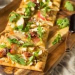 Flatbread pizza with garnish and one slice cut