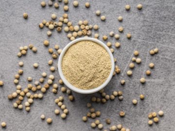 White ground pepper and whole peppercorn spice in a bowl.