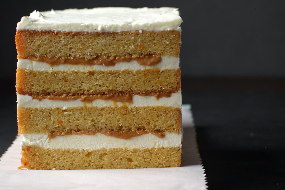 slice of orange cake with a dulce de leche and swiss meringue buttercream filling
