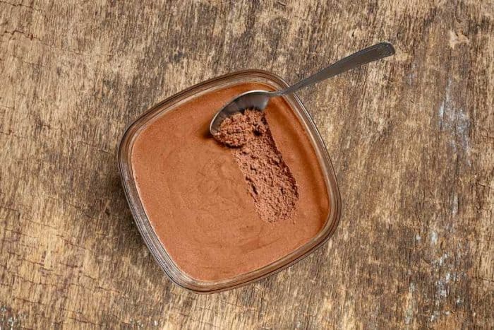 Traditional French chocolate mousse in a bowl and a spoon on the old wooden background