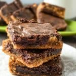 the chocolate peanut butter brownies stacked in a small white plate with the layers of chocolate and peanut butter visible