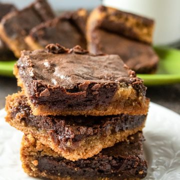 the chocolate peanut butter brownies stacked in a small white plate with the layers of chocolate and peanut butter visible