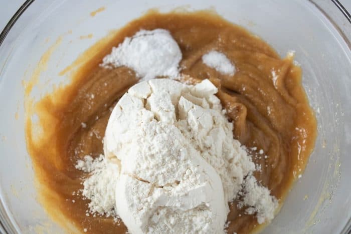 flour, baking powder and salt are added to a mixture of sugar, peanut butter and eggs in a large mixing bowl