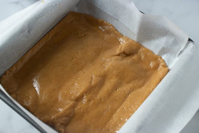 the peanut butter mixture is spread evenly on a baking pan with parchment paper