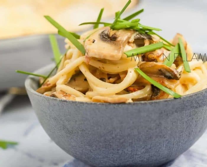 keto carbonara with Palmini noodles in a bowl topped with a green herbs