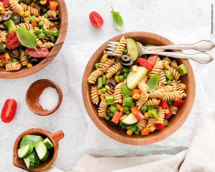 The al dente pasta is perfectly mixed with vegetables, including juicy cherry tomatoes, crisp bell peppers, corn, and Persian cucumbers with added basil and olive oil