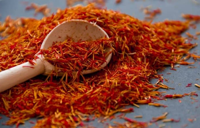 Saffron scattered on a table in a wooden spoon on a dark background