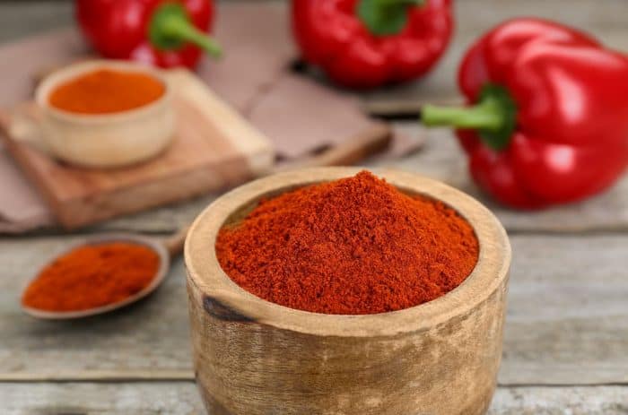 Bowl with aromatic paprika powder on wooden table