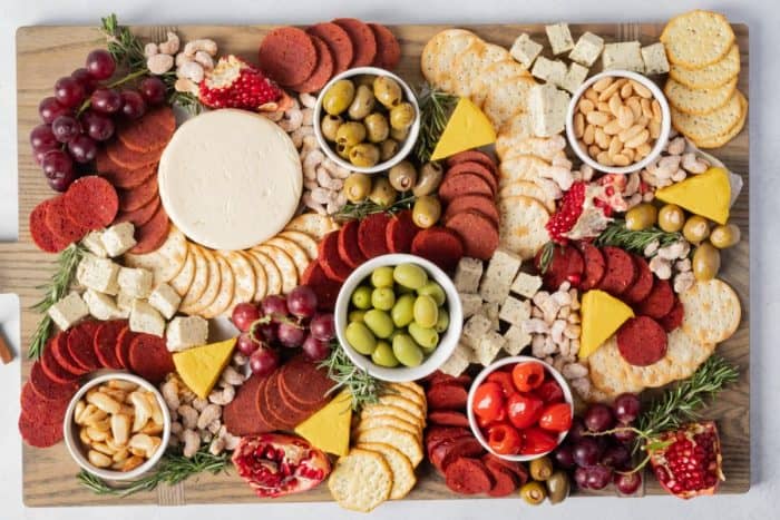 vegan Christmas charcuterie board idea with fruits, tofu, olives, cheese, crackers, nuts, herbs, and vegan meats