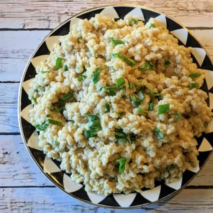 a plate of tiny star-shaped pasta dances in a delicate balance of garlic- and green onion-infused plant butter