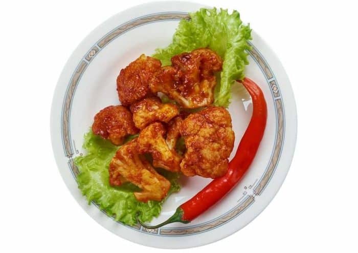 a Korean side dish made of cauliflowers in a mix of gochujang, soy sauce, and minced garlic with fresh lettuce and chili on the side