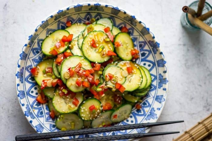 a bowl of thick cucumber slices and bell peppers are dressed in a vinaigrette that perfectly blends tangy, sweet, spicy, and salty flavors with rice vinegar, caster sugar, soy sauce, and gochugaru.
