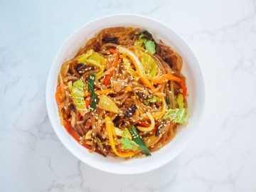 Bursting with umami flavors, this spicy vegan japchae is made with a stir-fried blend of sweet potato glass noodles, vibrant vegetables, earthy shiitake mushrooms, and a fiery gochujang-based sauce.