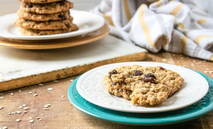 a white plate with a piece of oatmeal raisin cookie on a dinner table