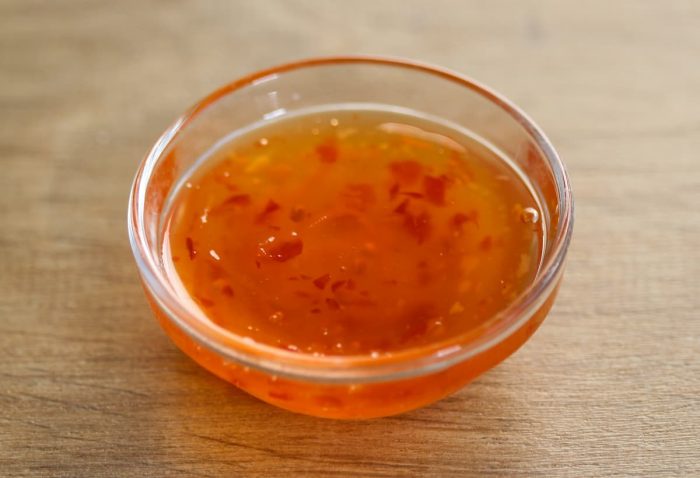 a bowl of fruity sauce made from blend of fruits like plums, apricots, and peaches, duck sauce provides a delightful fruity flavor on a wooden table