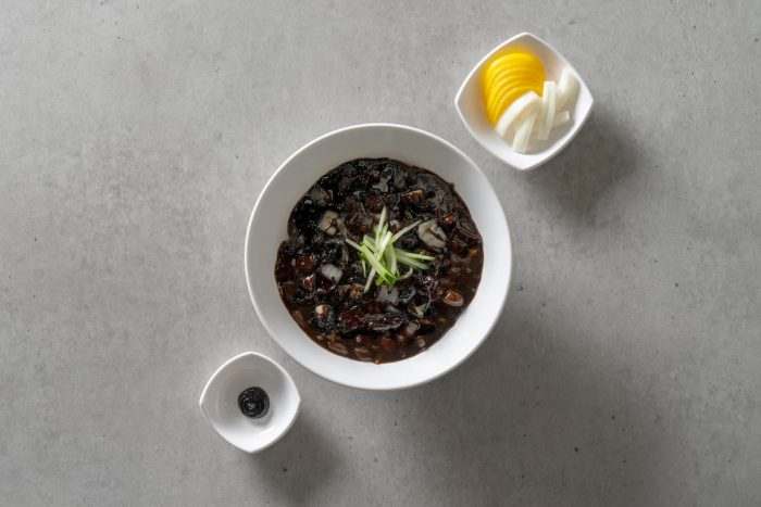 a bowl of Korean food dish black bean sauce with vegetable sidedish on the sides