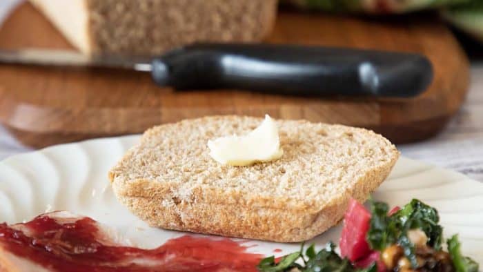 image focused on  sourdough discard yields a slightly sweet, wheat-infused, delectably light loaf with butter on top