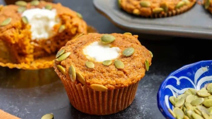  yummy muffins are made with pumpkin puree, pumpkin pie spices, and sourdough discard. They are filled with cream cheese frosting and have pumpkin seeds