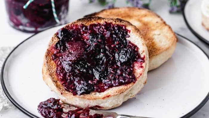 homemade sourdough English Muffins topped with blueberry placed on a white plate