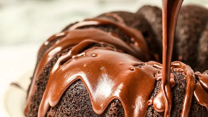 close up image of sourdough discard chocolate cake being drizzled with chocolate