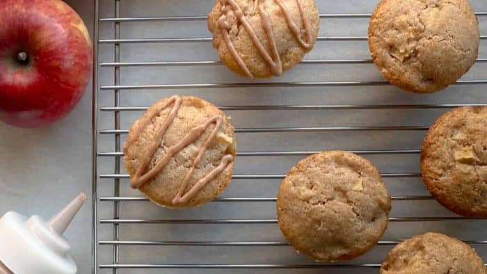 These muffins, made with sourdough discard, contain several delicious apples and are moist and delicious are freshy baked and on a cooling rack