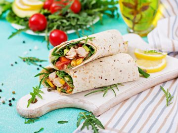 Burritos wraps with chicken and vegetables on light background.