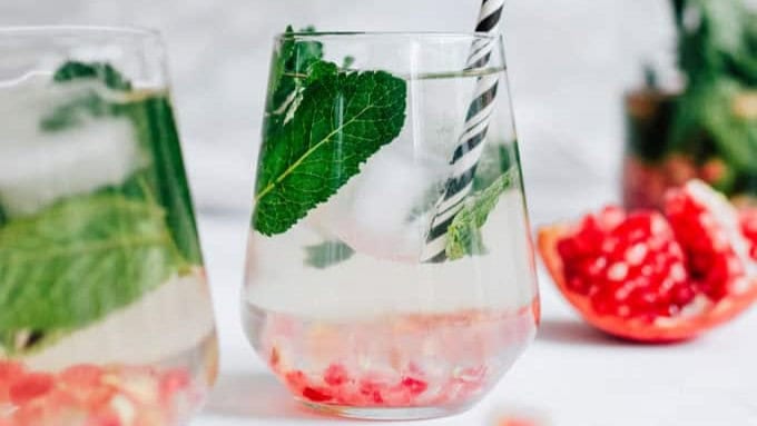 a glass of this holiday detox drink, made with fiber-rich, anti-inflammatory pomegranate seeds, mint, honey, and water