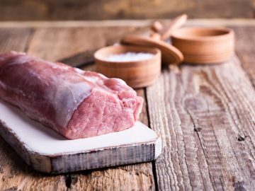 Organic pork meat on chopping board ready for cooking, rustic style, selective focus