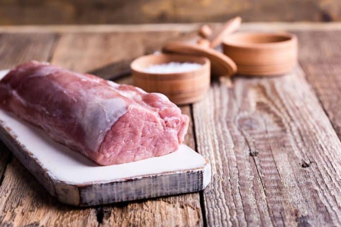 Organic pork meat on chopping board ready for cooking, rustic style, selective focus