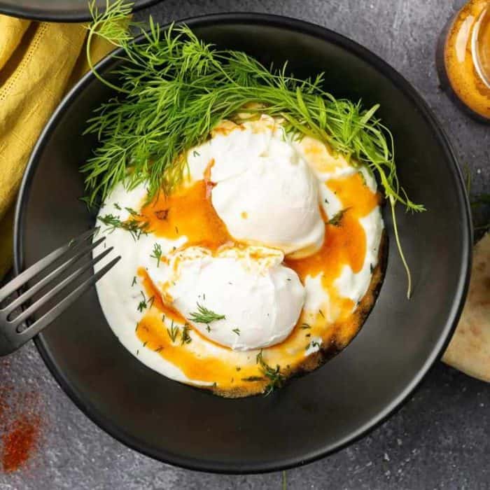 With poached eggs on a bed of spiced, garlicky Greek yogurt, it boasts an irresistible combination of runny yolks and creamy yogurt on a black bowl