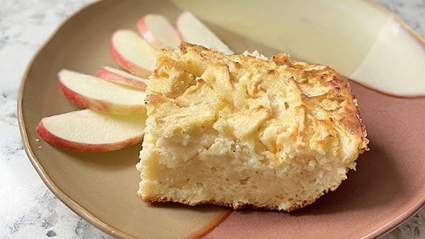 a plate of this Greek yogurt apple cake with slices of fresh apple on the sides