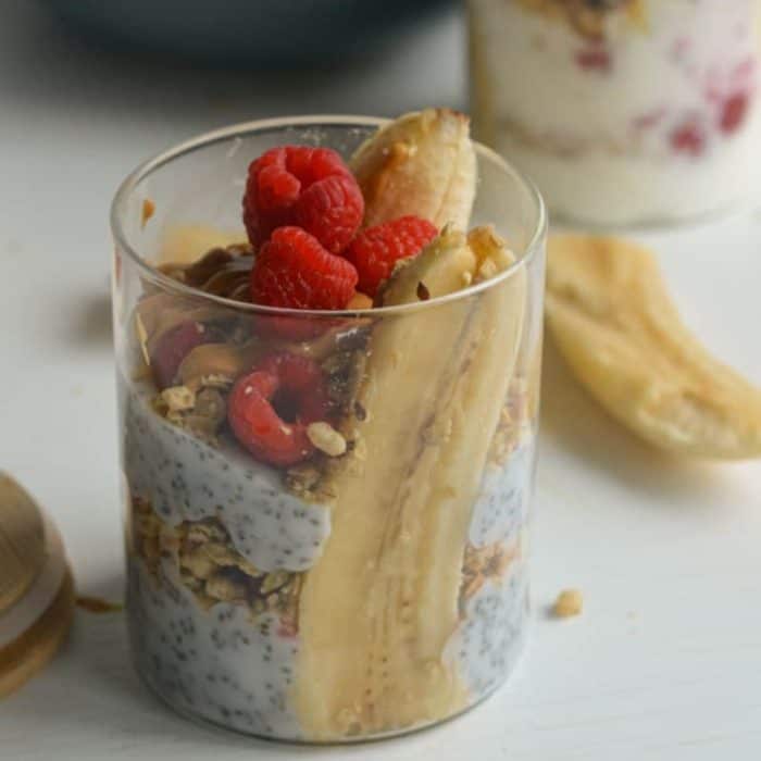 Greek yogurt into a glass jar with two banana halves along the sides, then top with berries, low-sugar jam, granola, and peanut butter