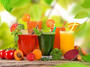 different flavored of freshly made detox juice with fresh vegetables and fruits on the sides