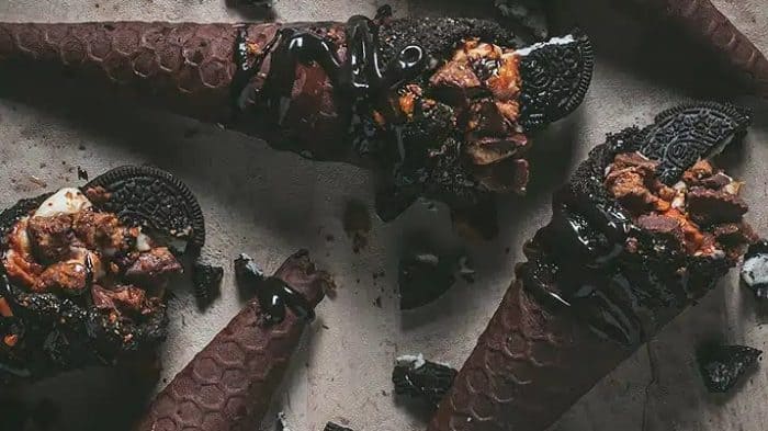 Each cone is handmade with the help of a waffle cone maker, dipped into melted chocolate and crushed Oreos, and filled with a cream cheese filling that has chopped Reese’s peanut butter cups and Butterfingers