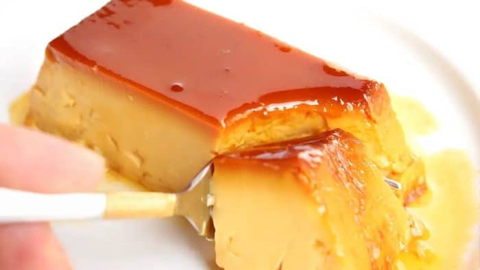 a person eating this flan it is a sumptuous dessert with a silken texture and a deep caramel flavor