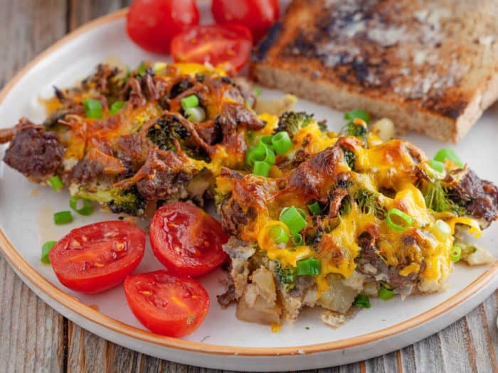sausage and potato breakfast casserole with sliced tomatoes and toasted bread on a plate
