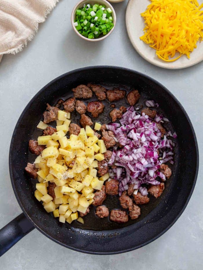 cooked sausage in a pan with onion and diced potatoes