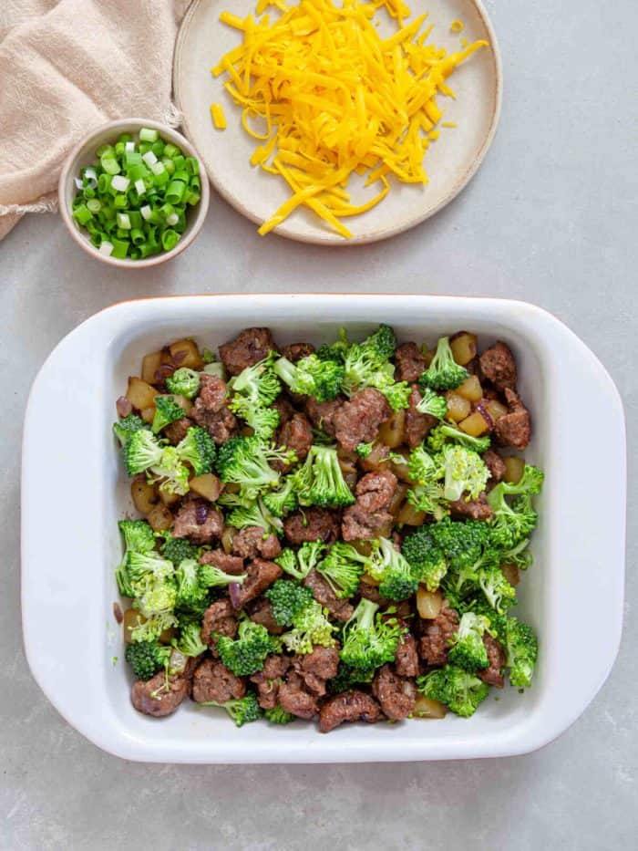 cooked sausage, potato, and diced broccoli assembled in a baking dish