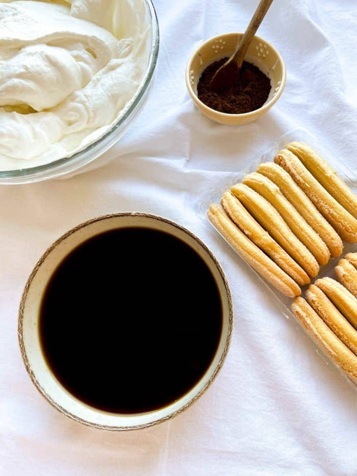 a bowl of espresso with ladyfingers on the side