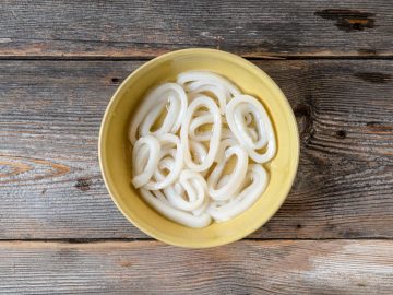 Begin by marinating the calamari in a mixture of sparkling water, lemon juice, baking soda, sugar, and salt, then chill it in the refrigerator for 2.5 hours.