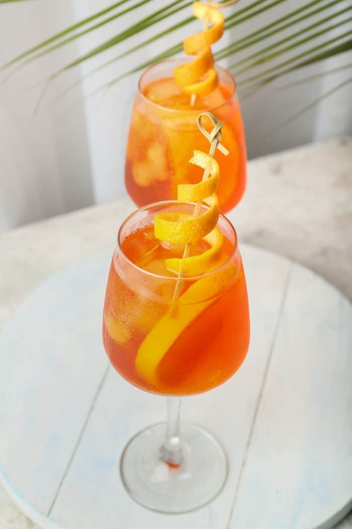 Glasses of Aperol spritz cocktail on light background