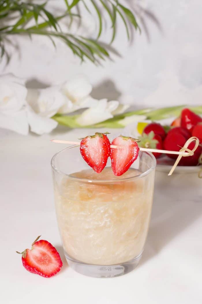 Drink with a shiny shimmer in a glass decorated with strawberry wedges