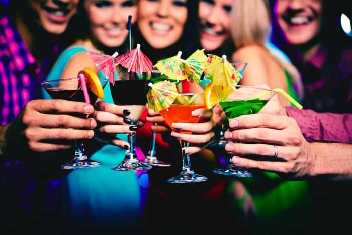Cocktails held by happy friends at party