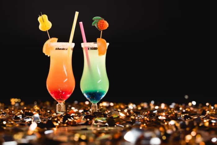 Sweet cocktails with straws on golden confetti with copy space