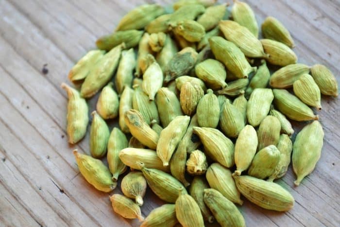 Green cardamom seeds in shape of circle on wooden table