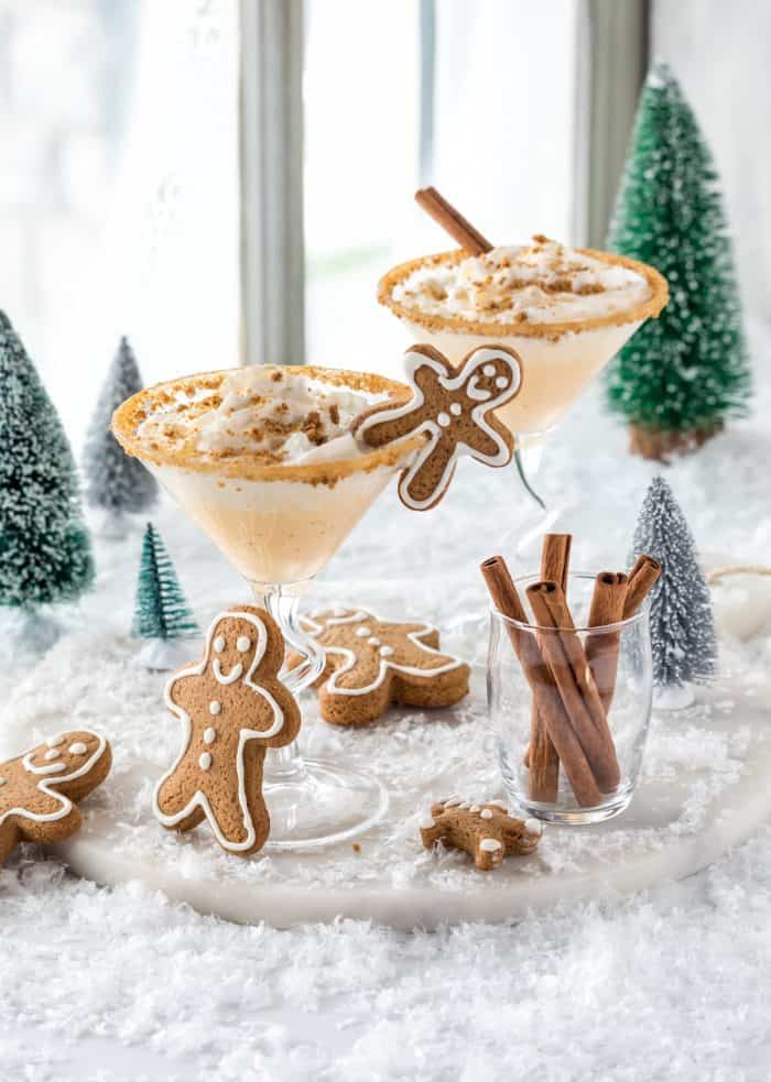 Two glasses of gingerbread martinis with whip cream and gingerbread cookies.
