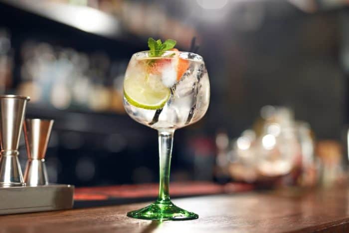 Cocktail Drink In Bar Close Up. Glass Of Gin Tonic Cocktail With Lime And Mint On Bar Counter. 