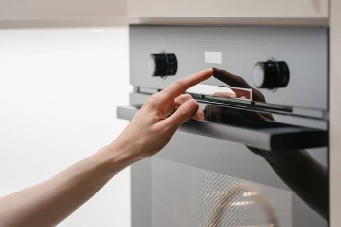 Woman press button on touchscreen display at modern electric oven.