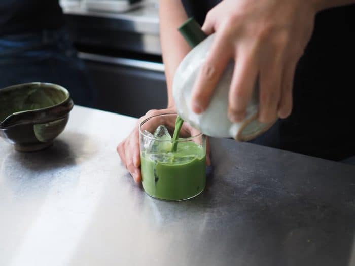 Matcha, green tea - Barista pouring Matcha to a glass of ice with traditional japanese matcha tools. selective focus.
